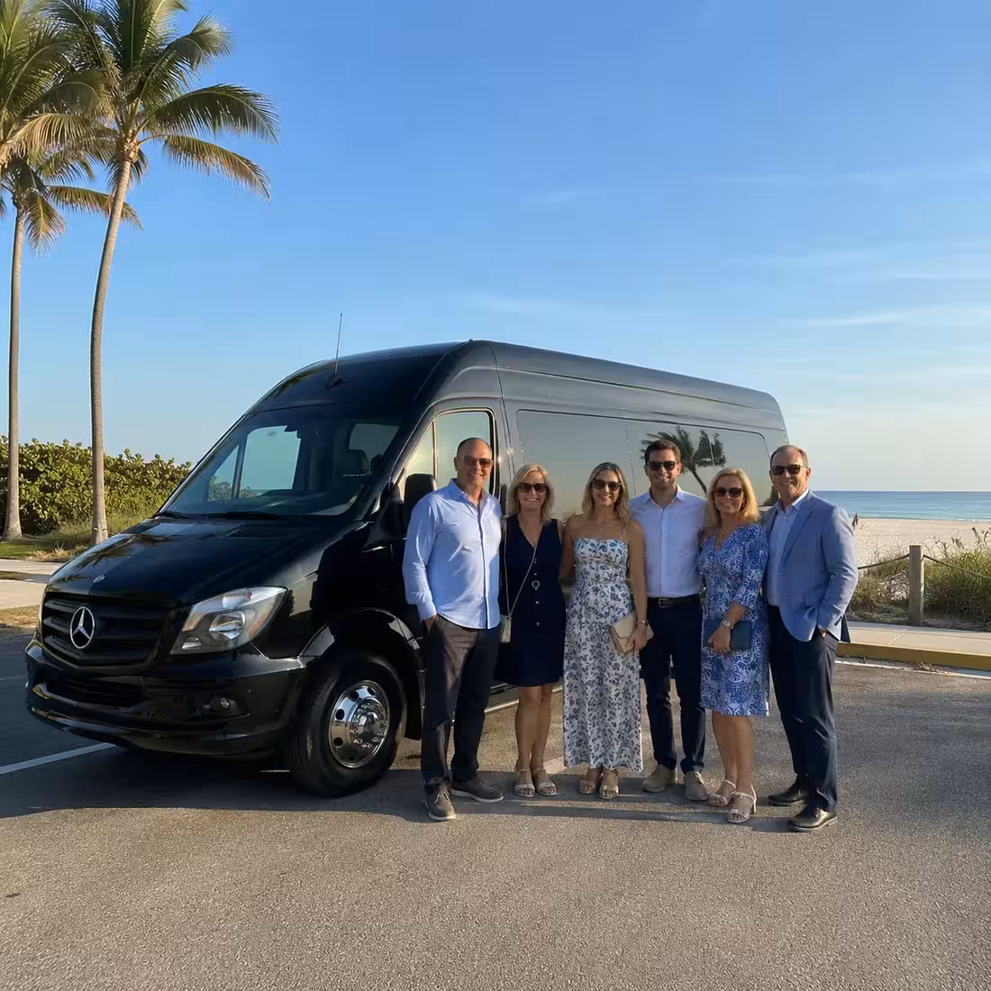 Group beside a Mercedes Sprinter limo from the Naples fleet at the beach