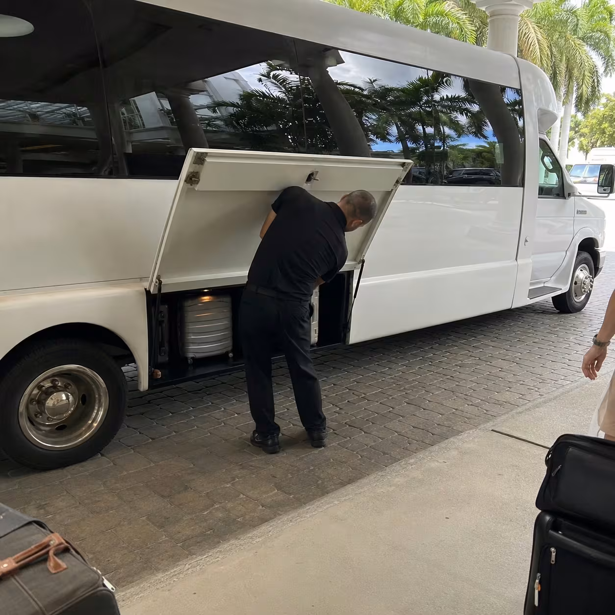 Chauffeur loading suitcases into a minibus luggage bay for an airport transfer in Naples, Florida