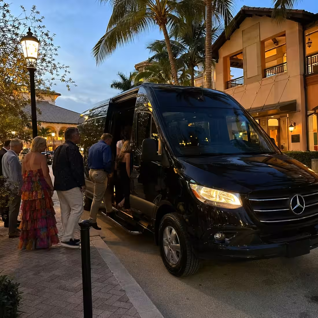 Black Sprinter limo picking up guests in a North Naples Mercato dining district at dusk