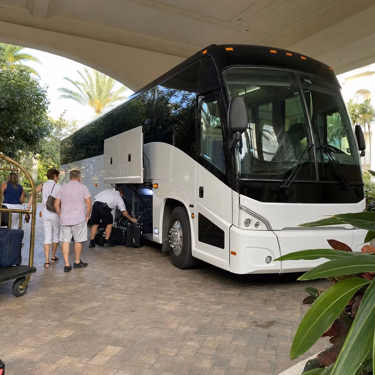White MCI J4500 motorcoach loading luggage at a Naples resort hotel porte-cochere