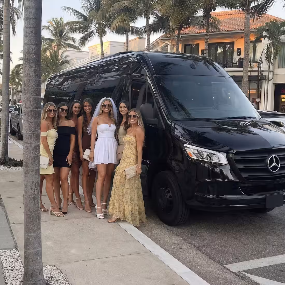 Black Sprinter limo at a palm-lined Fifth Avenue South curb for a Naples bachelorette party