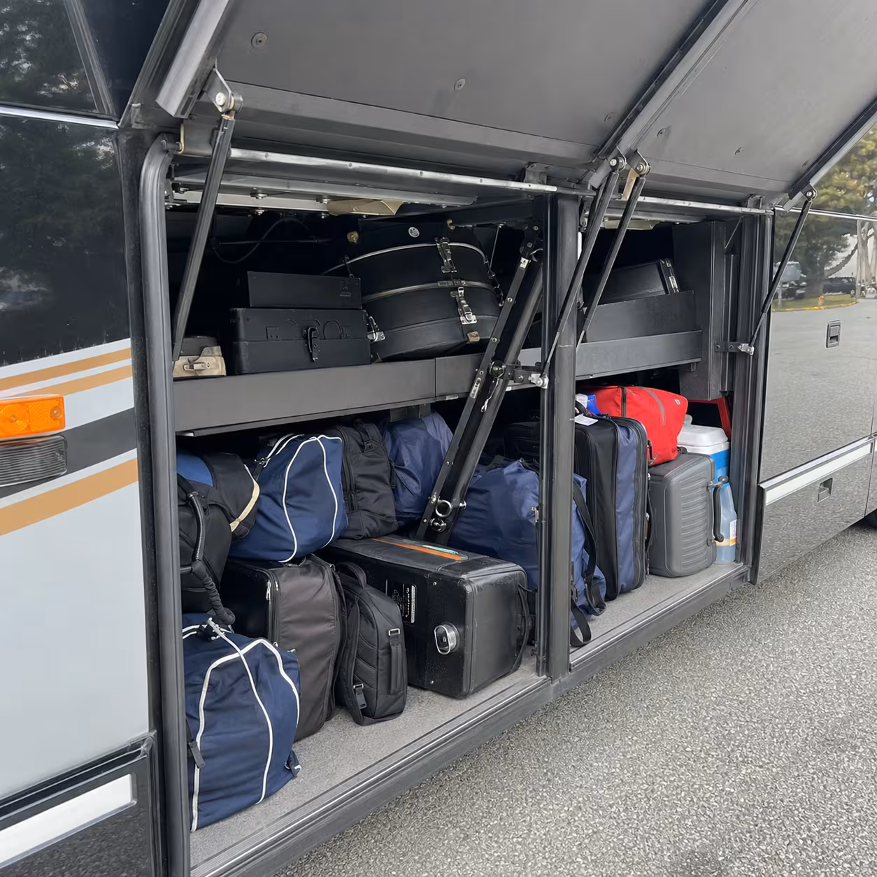 Sports and band equipment stowed in a motorcoach luggage bay for a Naples school trip
