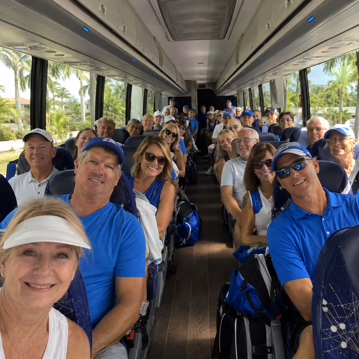 Team seated with duffel bags aboard an MCI motorcoach for a Naples sporting event