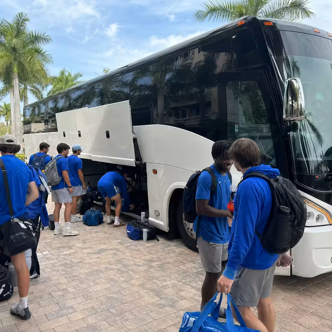 Sports equipment loaded in a motorcoach luggage bay for a Naples team trip