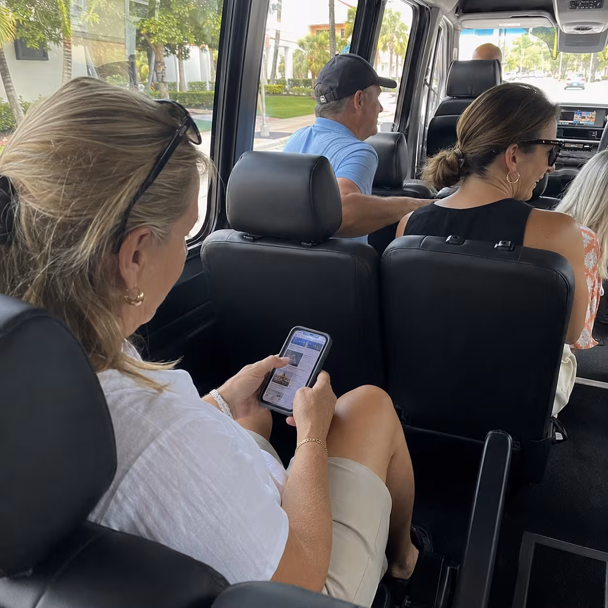 Guest checking the tour itinerary on a phone inside a minibus in Naples, Florida